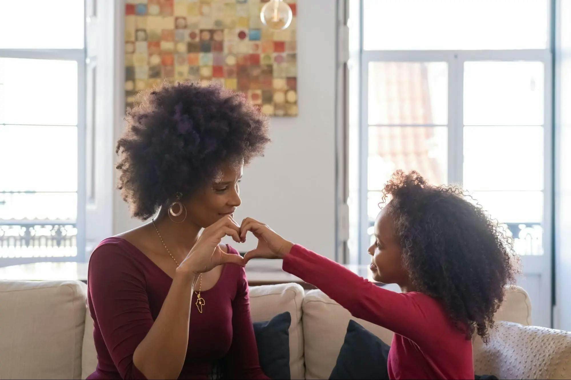 Mom and daughter making a heart shape with their hands